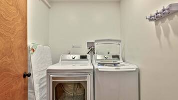 A laundry room with two stacked washers and dryers, a wooden door, and a towel rack on the wall.