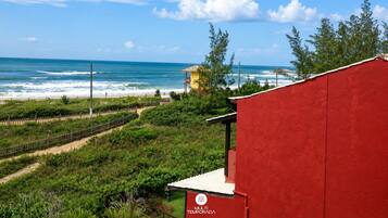 Edificio rojo con un letrero que dice 'MULTI TEMPORADA' frente a una playa con olas y cielo despejado.