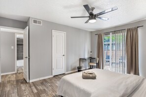 Ein Hotelzimmer mit Bett, Schreibtisch, Stuhl, Deckenventilator und Blick ins Freie.