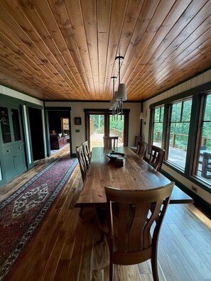 Ein Esszimmer mit einem langen Holztisch, Stühlen und einem Teppich.
