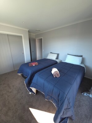 Une chambre d’hôtel avec deux lits, une porte et un sol recouvert de moquette.