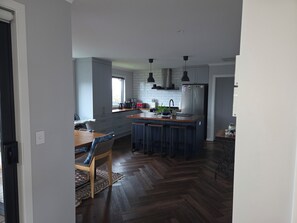 A modern kitchen with a central island, bar stools, a dining table, and a herringbone wood floor. - Cosy and modern holiday retreat in beautiful Taupō (Taupō)