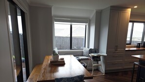 Una cucina moderna con zona pranzo, una finestra con tende e vista all'esterno.