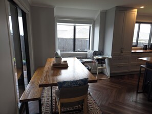 A modern kitchen with a dining area, a window with blinds, and a view of the outside. - Cosy and modern holiday retreat in beautiful Taupō (Taupō)