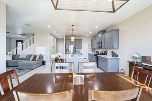 Una cocina moderna con armarios grises, una isla central y un comedor con mesa y sillas de madera.