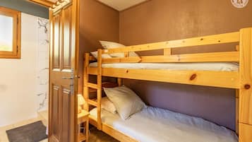 A bunk bed room with a wooden door, a small table with a lamp, and a marble-patterned wall.
