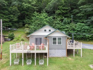 A small house with a porch, numbered 441, surrounded by a forest. - Mill Timber Lodge: Creekfront home, dog friendly, firepit, yard, deck, WiFi & grill! (Newland)