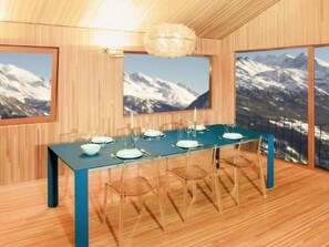 Ein Essbereich mit Tisch für vier Personen, Holzwänden und Blick auf die Berge.