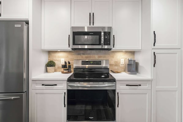 A modern kitchen with stainless steel appliances, including a refrigerator, microwave, and oven.