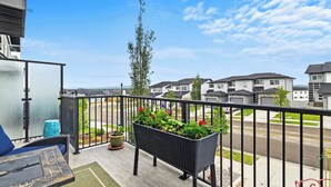 A balcony with a table, chairs, and a planter with flowers. - On The Ridge | Sleeps 8 | A/C | Gym Equipment | (Sylvan Lake)