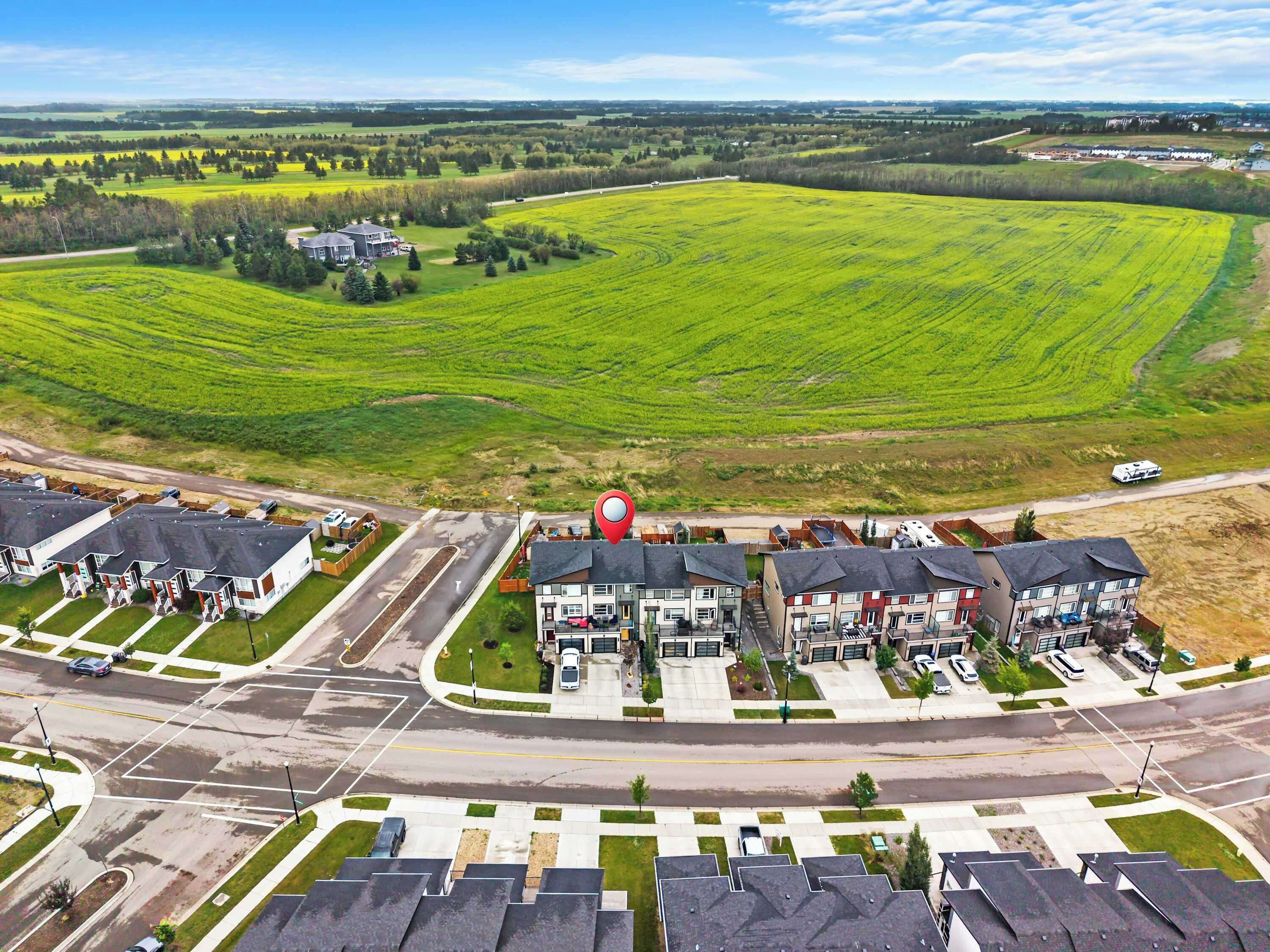 A residential area with multiple apartment buildings, a central road, and surrounding green fields.