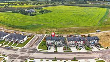 A residential area with multiple apartment buildings, a central road, and surrounding green fields.