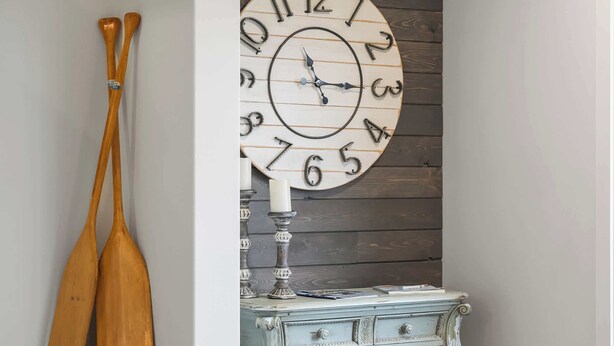 A staircase with a decorative clock, wooden paddles, and a vintage console table. - On The Ridge | Sleeps 8 | A/C | Gym Equipment | (Sylvan Lake)