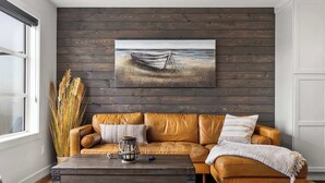 Un salon avec un canapé en cuir marron, une table basse et un tableau représentant un bateau accroché au mur.