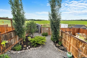 A fenced backyard with a gravel path, a small shed, and a wooden fence.