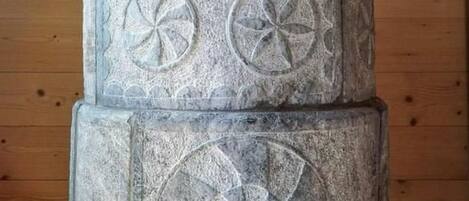 A stone pillar with carved symbols and text, set against a wooden background.