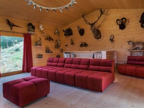 A room with a wooden ceiling, a red sofa, and various animal taxidermy mounted on the walls. - Exklusives Architektur-Chalet in toller Lage by Interhome (St-Martin VS)