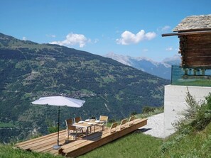 A wooden deck with a table and chairs, overlooking a mountainous landscape. - Exklusives Architektur-Chalet in toller Lage by Interhome (St-Martin VS)