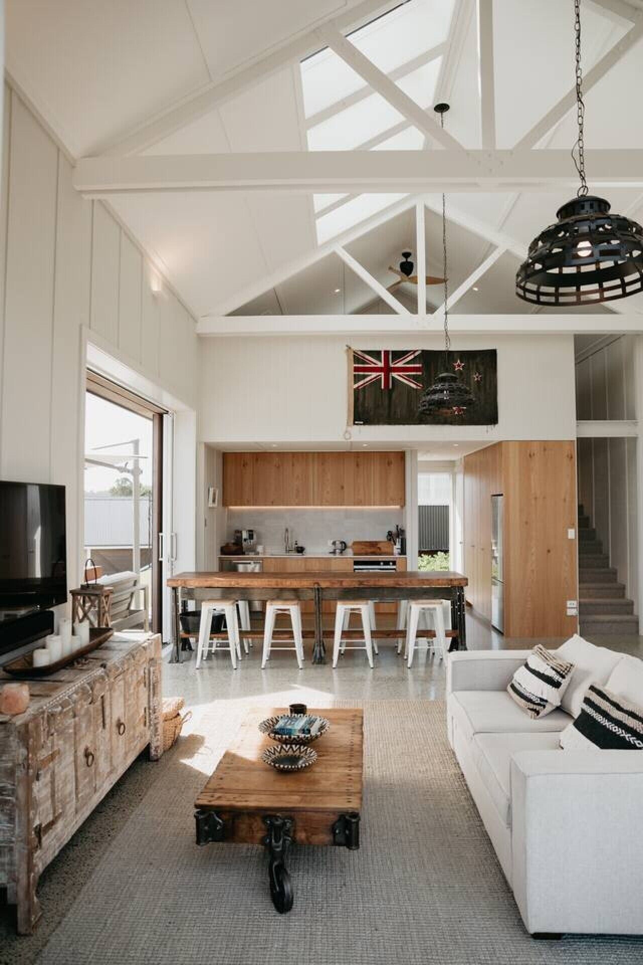 Een moderne keuken met witte kasten, een houten eiland en een zwarte hanglamp.