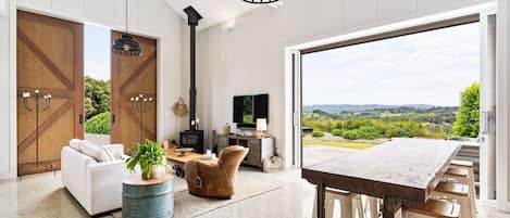 A spacious living room with a large window, a fireplace, and a dining area.