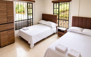 A bedroom with two beds, wooden headboards, a nightstand, and a wardrobe.