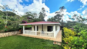 A small house with a red roof, white exterior, and a white balcony.
