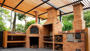 A brick-built outdoor kitchen with a chimney, a sink, and a wood storage area.
