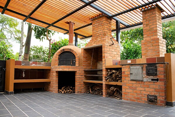 A brick-built outdoor kitchen with a chimney, a sink, and a wood storage area.