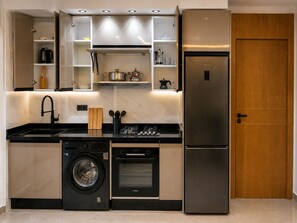A compact kitchen with a built-in washing machine, oven, and a stainless steel refrigerator. - Modern 1BR Netflix • WiFi • Free Parking (Tangier)