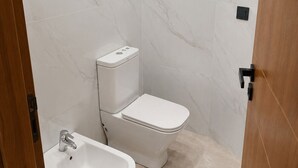 A bathroom with a toilet, bidet, and sink, all in white. - Modern 1BR Netflix • WiFi • Free Parking (Tangier)