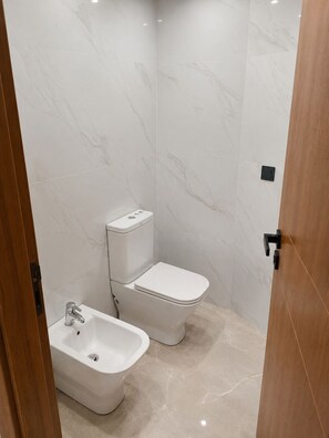 A bathroom with a toilet, bidet, and sink, all in white. - Modern 1BR Netflix • WiFi • Free Parking (Tangier)