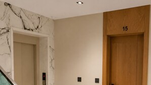 A hallway with a marble wall, a wooden door labeled '15', and a glass staircase. - Modern 1BR Netflix • WiFi • Free Parking (Tangier)
