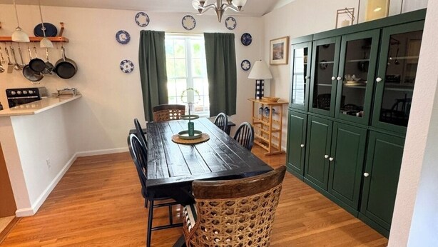Un comedor con mesa de madera, sillas y una araña.
