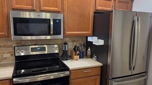 Una cocina con electrodomésticos de acero inoxidable, armarios de madera y salpicadero de azulejos.