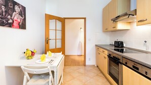 A kitchen with a dining table, chairs, a fruit bowl, a toaster, and wooden cabinets.