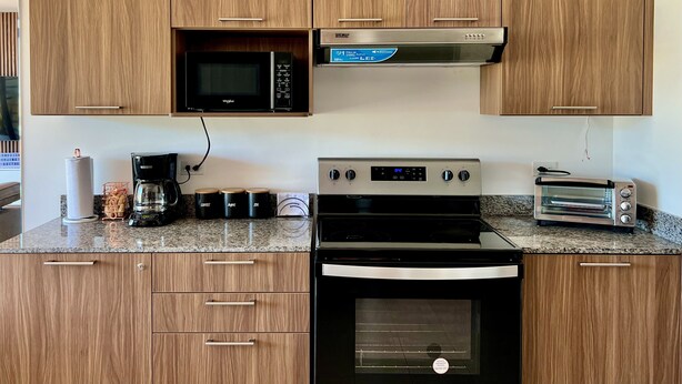 Una cucina con mobili in legno, un forno a microonde, una macchina per caffè, un tostapane e un forno.