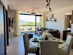 Ein modernes Wohnzimmer mit Essbereich, großen Fenstern und Blick auf die Stadtlandschaft.