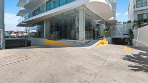 A modern building with a curved glass facade, a ramp leading to the entrance, and a clear sky. - Luxury in Marina Vallarta Gym Roof Pool (Puerto Vallarta)