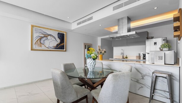 A modern kitchen with a glass dining table, grey upholstered chairs, and a marble backsplash. - Luxury in Marina Vallarta Gym Roof Pool (Puerto Vallarta)