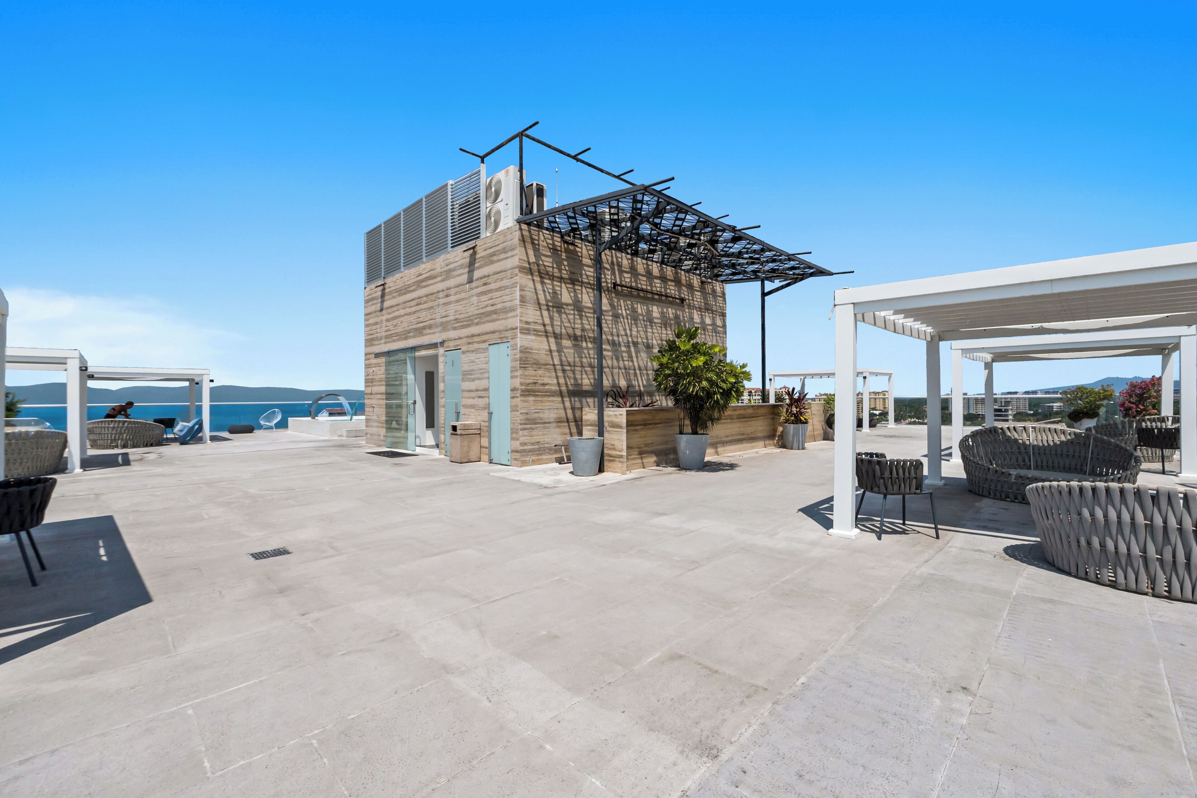 A rooftop terrace with outdoor seating, a pergola, and a view of the sea.