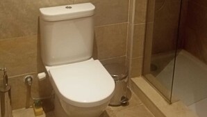 A standard bathroom with a toilet, a shower enclosure, and a small shelf with a roll of toilet paper. - 
    Marassi Marina 1 Sea View (Marsa Matrouh)