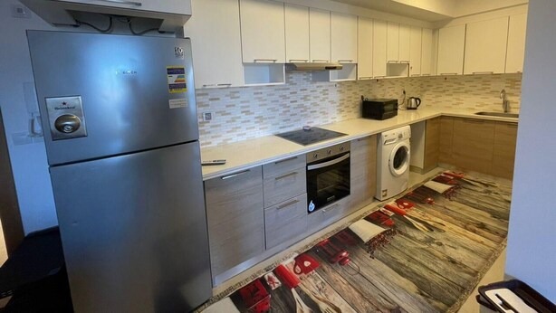 A modern kitchen with a stainless steel refrigerator, a built-in oven, a microwave, and a washing machine. - 
    Marassi Marina 1 Sea View (Marsa Matrouh)