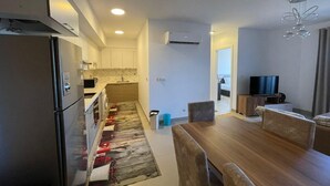 A modern kitchen with a refrigerator, microwave, and sink, leading to a dining area with a wooden table and chairs. - 
    Marassi Marina 1 Sea View (Marsa Matrouh)