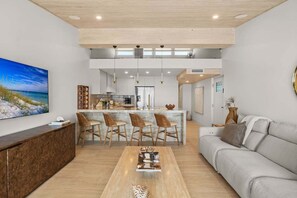 Ein modernes Wohnzimmer mit einer Couch, einem Couchtisch und einer Küche im Hintergrund.