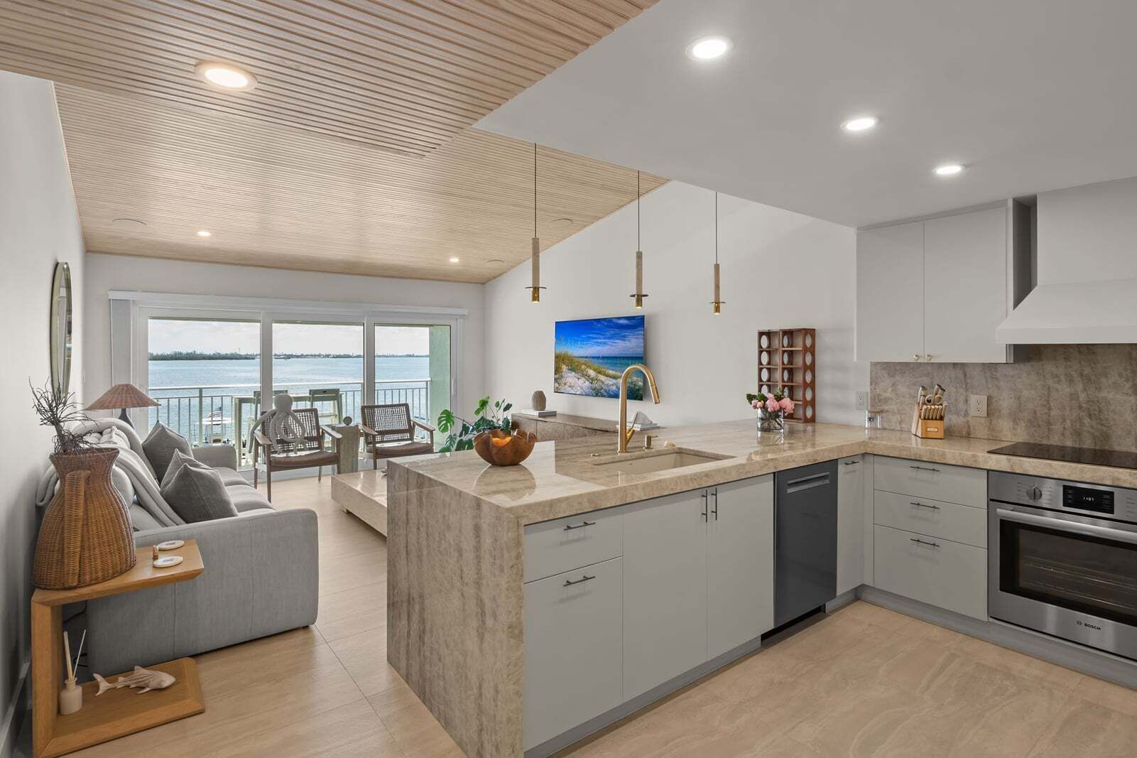 A modern kitchen with a central island, built-in appliances, and a view to the outside.