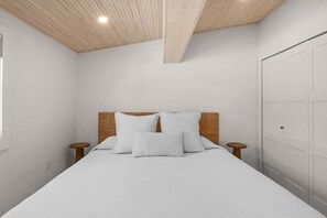 Ein Schlafzimmer mit einem Bett, einem Holzkopfteil, zwei Nachttischen und einem Kleiderschrank.