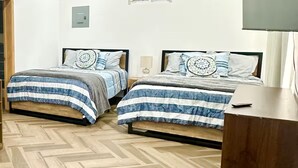Un dormitorio con dos camas, ventilador de techo, aire acondicionado y televisor.
