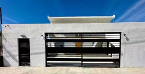 A modern building with a white facade, a large garage door, and a clear blue sky. - Depa Azul+Green Spot, Entire Duplex, 4BR-Sleeps 12 (Puerto Peñasco)