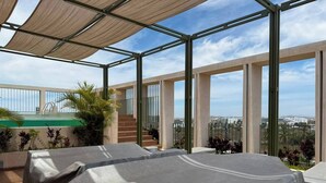Une terrasse sur le toit avec deux tables abritées, une piscine et une vue sur la ville.