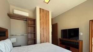 Une chambre d’hôtel avec un grand lit, une télévision, une armoire et une étagère intégrée.
